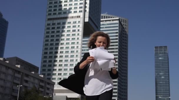 Concept d'équilibre travail-vie personnelle. Une jeune employée jette en l'air ses papiers devant des immeubles de bureaux — Video