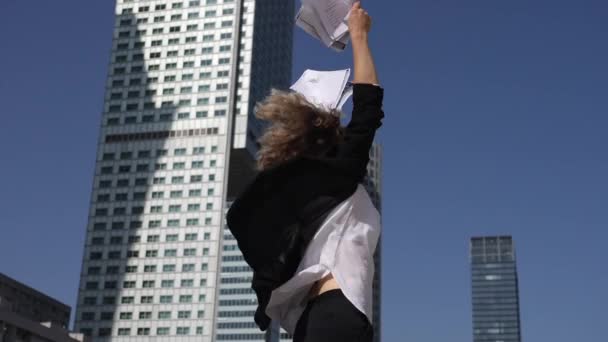 Jeune femme de carrière extrêmement excitée pour son succès professionnel saute tenant des papiers dans les mains — Video