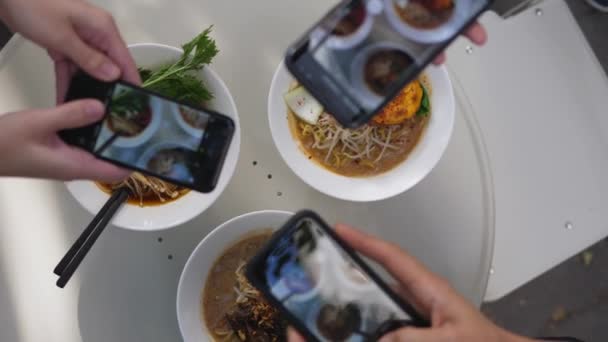 Zamknij się z trzech telefonów strzelanie białe talerze z wegańskiej ramen podzielić się na portalach społecznościowych. Specjalność restauracji azjatyckiej — Wideo stockowe