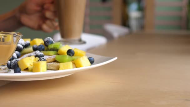 Πρωινό με τηγανίτες με φρούτα, μούρα, φυστικοβούτυρο και καφέ λάτε. — Αρχείο Βίντεο