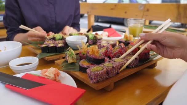Duas pessoas comendo deliciosos rolos de sushi vegan, mergulhando em molho de soja no início. Comida saudável de rua vegan — Vídeo de Stock