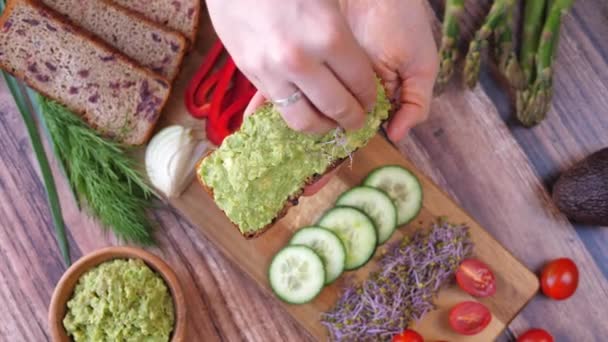 Hacer tostadas de aguacate para un desayuno vegano saludable Poniendo brotes frescos en la parte superior. — Vídeos de Stock