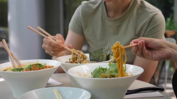 Dos chicas comiendo sus deliciosas sopas tradicionales japonesas de ramen. Amigos disfrutando del almuerzo juntos en el restaurante asiático — Vídeo de stock