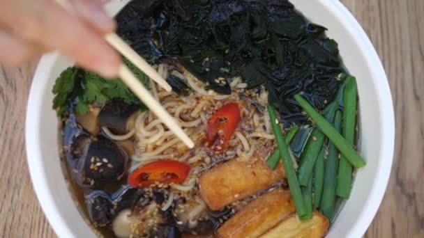 Top shot of chopsticks pulling noodles out of vegan ramen soup. Healthy organic vegan diet — Stock Video