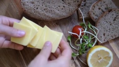 Çavdar ekmeğinin ve sebzelerin yanına vejetaryen peyniri dilimleyen eller. Kırsal tarzda sağlıklı organik vegan kahvaltısı..