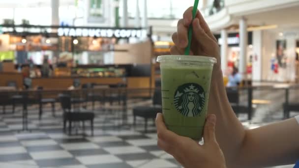 Starbucks coffee. Putting plastic straw in take away cup of matcha green tea and stirring it. Warsaw-Poland-August 2020 — 图库视频影像
