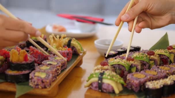 Sushi vacsora. Az oldalsó képen két kéz szusi tekercset eszik evőpálcikával. Kézműves ázsiai konyha — Stock videók