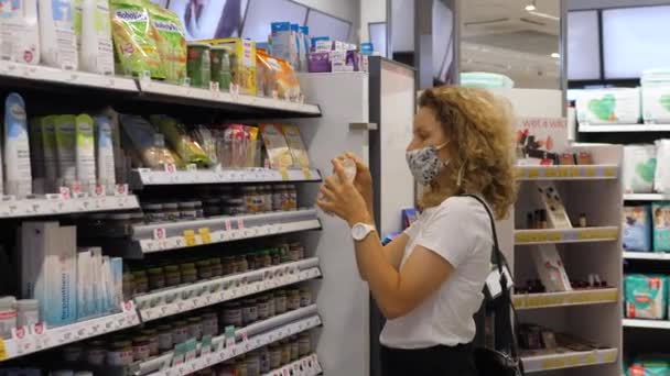 Femme faisant du shopping dans un masque facial dans un magasin de soins de santé pendant la pandémie de Covid-19. Allées avec crèmes et couches. Juillet 2020-Varsovie-Pologne — Video