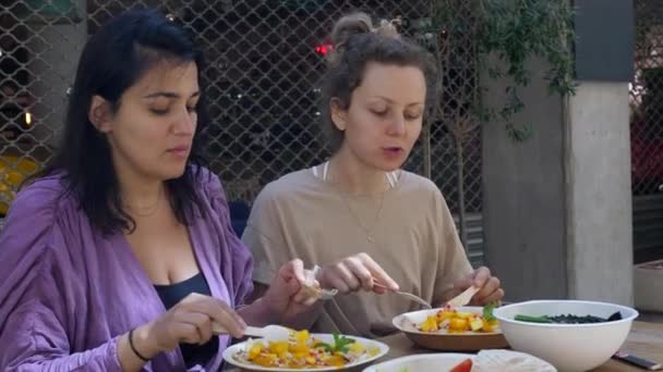 Tempo di qualità con gli amici. Due ragazze che godono di chat e le loro frittelle vegan organici sani con frutta. Stile di vita vegano sano ed equilibrato. — Video Stock