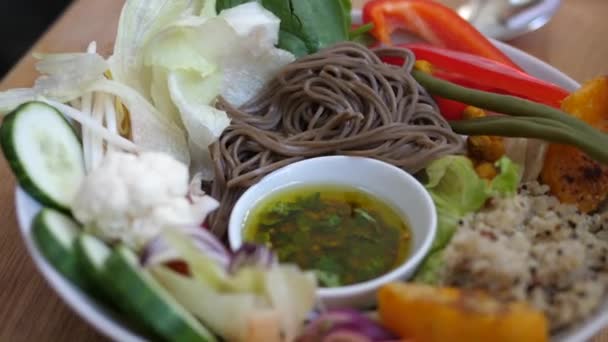 Πιρούνι που βουτάει μια γλυκοπατάτα στο ντρέσινγκ σαλάτας. Υγιεινό βιολογικό vegan γεύμα με noodles, δημητριακά και λαχανικά σερβίρεται σε λευκό πιάτο. — Αρχείο Βίντεο