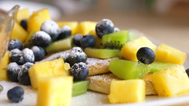Ahornsiroop gieten op pannenkoeken met fruit en bessen. Sluitingsdatum. — Stockvideo