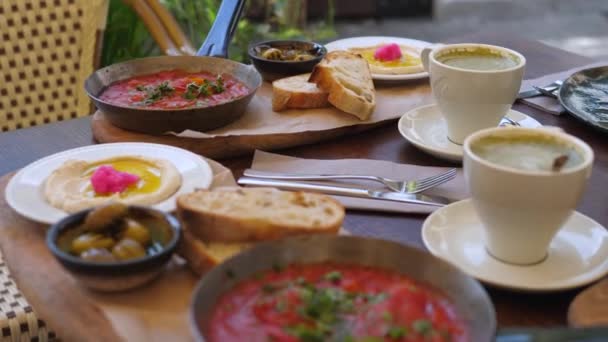 Különböző vegán közel-keleti reggeli két személyre. Gluténmentes pirítós hummussal és shakshukával, matcha lattéval a fedélzeten. — Stock videók