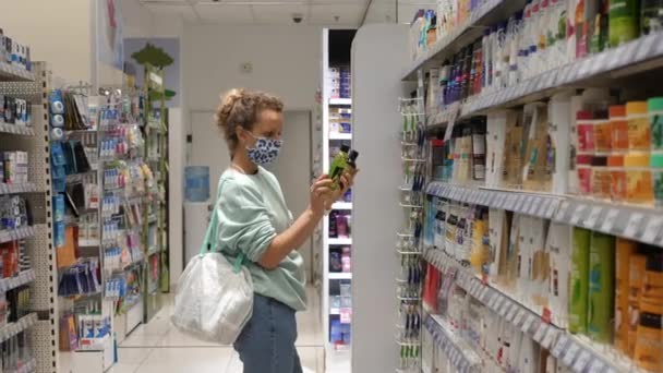 Ψώνια σε φαρμακείο κατά τη διάρκεια πανδημίας. Γυναίκα επιλέγει σαμπουάν σε ένα τμήμα ομορφιάς και περιποίησης δέρματος. WArsaw-Πολωνία-2020 — Αρχείο Βίντεο