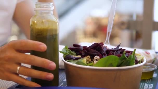 Main prenant une bouteille de smoothie vert. Déjeuner végétalien sain au food court : smoothie vert et salade. Aliments sains prêts à manger — Video