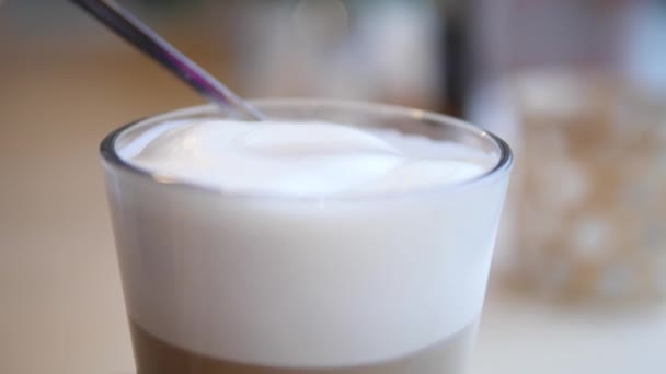 Σκούπισμα παχύ αφρό από ένα νόστιμο ζεστό καφέ Latte με ένα κουτάλι σε ένα ποτήρι. — Αρχείο Βίντεο