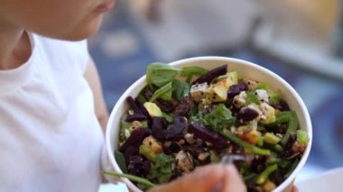 Çatalla lezzetli salata yiyen bir kadın. Bol yeşillikli vejetaryen salatası, yapraklar, pancar, tofu ve avokado. Sağlıklı yaşam tarzı kavramı. 