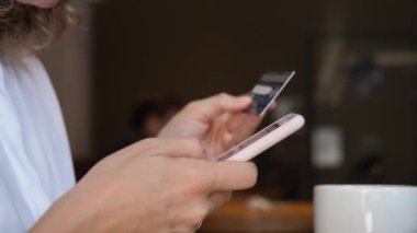 Çevrimiçi cep telefonu nakitsiz ödeme sistemi. Kafedeki akıllı telefondan sipariş veren genç bayana yakın çekim