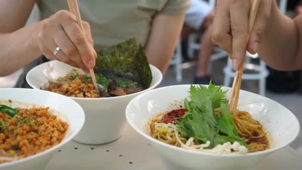Χέρια δύο ανθρώπων που βγάζουν νουντλς από σούπες ράμεν. Υγιεινή μοντέρνα ασιατική κουζίνα — Αρχείο Βίντεο