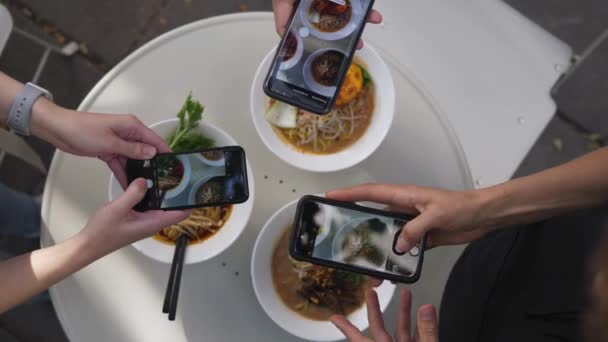 Asijské módní pouliční jídlo. Pohled shora na ruce fotografování chutné nudlové polévky na bázi rostlin — Stock video