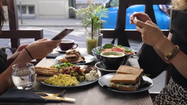 Almuerzo saludable hipster en la ciudad. Dos amigos blogueros de comida tomando fotos de su comida con smartphone. — Vídeo de stock