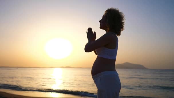 Έγκυος γυναίκα πρακτική γιόγκα στην παραλία στο ηλιοβασίλεμα. — Αρχείο Βίντεο
