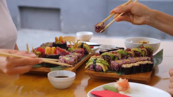 Dva lidé namáčejí sushi rohlíky do sójové omáčky a jí ji. Heathy asijské ulice jídlo — Stock video