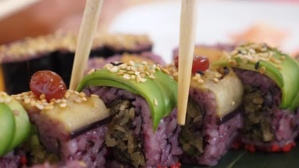 Sluiten van eetstokjes plukken een sushi roll uit de set. Heathy veganistisch Aziatisch eten — Stockvideo