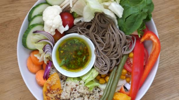 Ovanifrån av roterande platta med fullkornsnudlar, quinoa och olika grönsaker. Friska ekologiska vegan lunch — Stockvideo