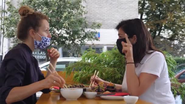 Dwie młode kobiety jedzące sushi w maskach na twarz podczas drugiej fali pandemii — Wideo stockowe