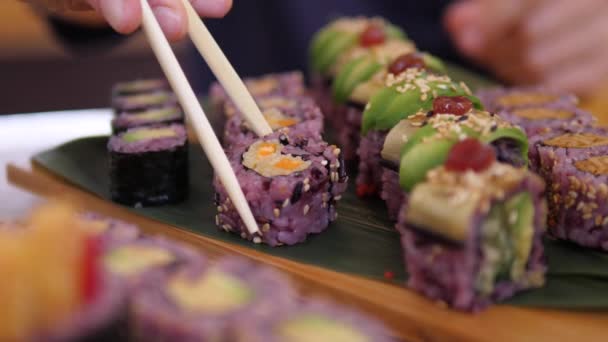 Zbliżenie pałeczki podnosząc kolorowe wegańskie sushi roll. — Wideo stockowe