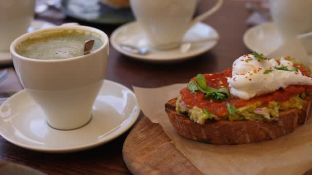 Wholegrain toast with avocado spread with shakshuka on wooden board served with coffee. Healthy vegetarian Middle Eastern breakfast — Stock Video