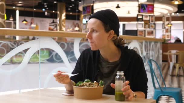 Mladá žena jí zdravý oběd a pití zeleného smoothie v jídelně nákupního centra. — Stock video