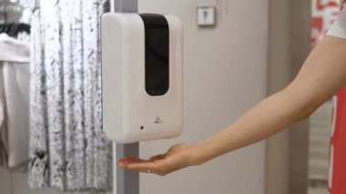 Kadın giyim mağazasında jöle kullanıyor. COVID-19 salgını sırasında alışveriş