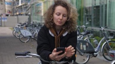 Sürdürülebilir kentsel hareketlilik. Toplu taşımacılıktan bisiklete binen genç bir kadın akıllı telefon uygulamasını paylaşıyor