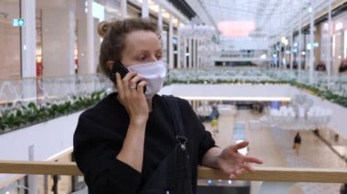 Covid-19 salgını sırasında alışveriş merkezinde maskeli bir kadın telefonda konuşuyordu.