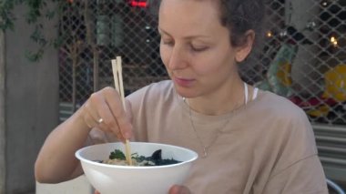 Sağlıklı vegan Asya mutfağı. Aç beyaz kız büyük bir zevkle vejetaryen ramen çorbası içiyor.. 