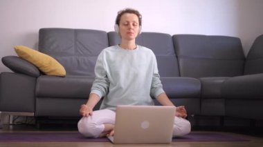 Coronavirus kilitleme kısıtlamaları. Kafkasyalı kadının evde online meditasyon uygulamasını ön planda tutmak.