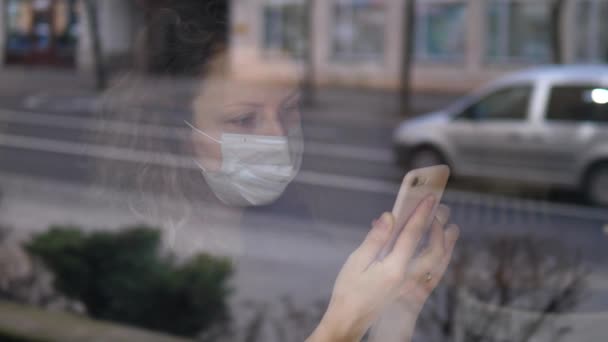 Het Coronavirus Epidemy. Vrouw in het masker met behulp van Smartphone tijdens het zitten in Cafe. — Stockvideo