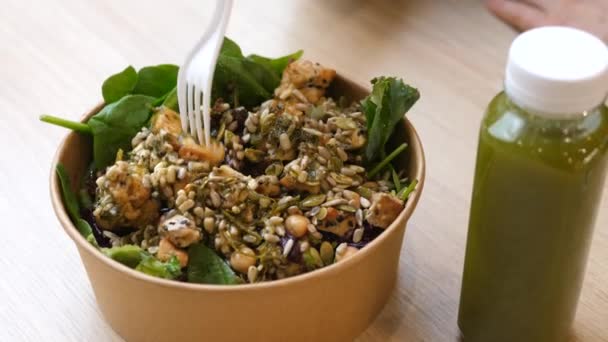 Main mangeant une salade à la fourchette. Déjeuner végétalien sain au food court, smoothie vert et un bol — Video