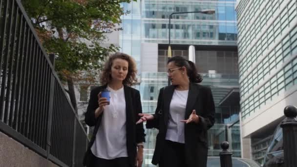 Conversación de dos mujeres de negocios fuera de edificios de oficinas. Pausa rápida para tomar café durante el día en el trabajo — Vídeo de stock