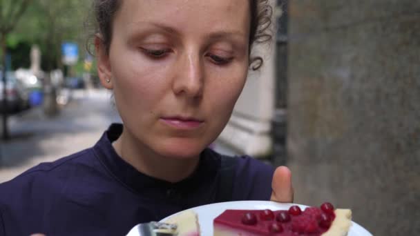 Nahaufnahme einer jungen Frau, die draußen ein Stück rohen veganen Himbeerkuchen probiert. Gesundes veganes Lebensstilkonzept mit Spaß — Stockvideo