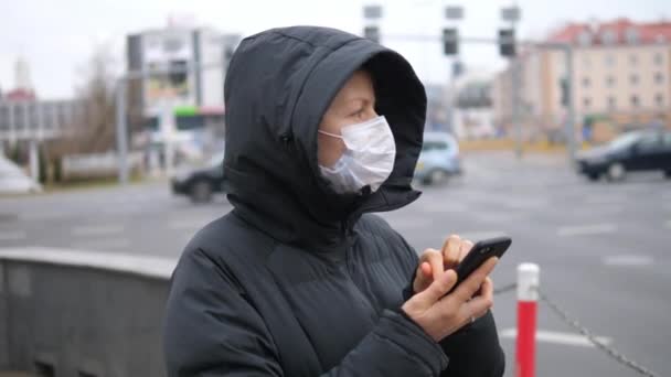 Mulher vestindo máscara facial e tosse enquanto usa celular na cidade. — Vídeo de Stock