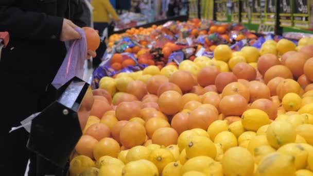 Kobieta wybiera owoce pomarańczowe w supermarkecie. Eko-torba wielokrotnego użytku na zakupy. Koncepcja zerowych odpadów. — Wideo stockowe