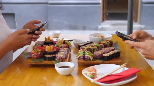 Dwoje ludzi przeglądających telefony podczas lunchu sushi unikając prawdziwej komunikacji. Technologia i stosunki. — Wideo stockowe