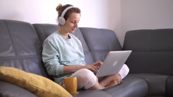 Självisolering under koronaviruskrisen. Ung kvinna fjärrarbetar på bärbar dator i hemmet miljö — Stockvideo