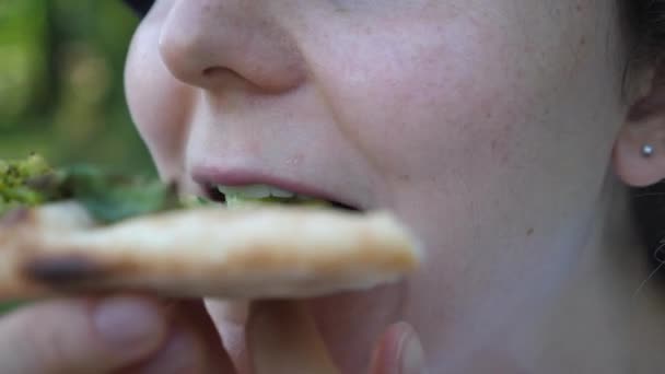 Hladová dívka jí plátek veganské pizza.Close up úst. Zdravé organické vegan street food koncept. — Stock video