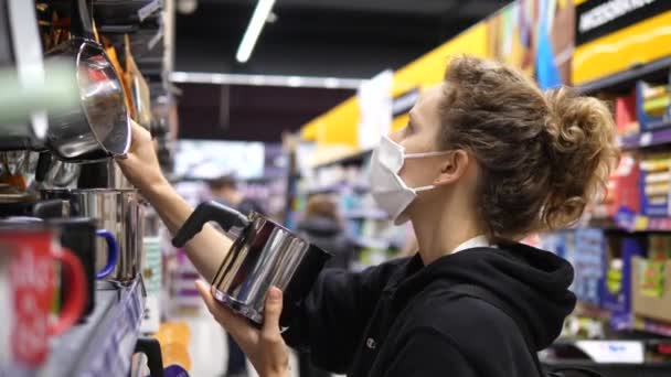 Вспышка коронавируса. Женщина-клиент в защитной маске в бытовом отделе. Концепция магазинов — стоковое видео