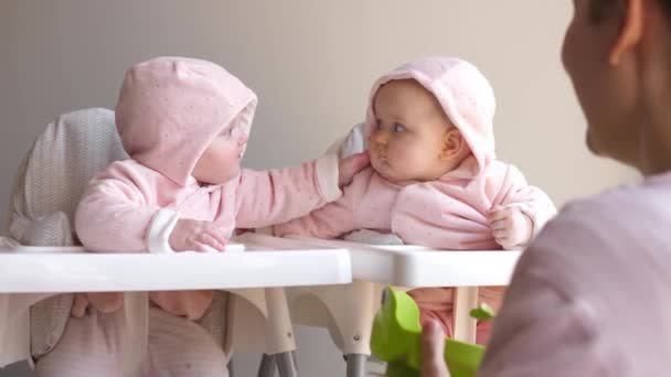 Ung mor fodrer sine tvilling babyer sidder på hår stole. Baby mad koncept. – Stock-video