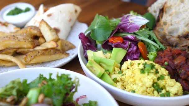 Variété de différents bols végétaliens sains délicieux de légumes, légumes verts, omelette de tofu et ailes de pomme de terre. — Video