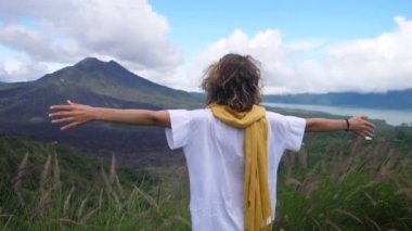 Batur Dağı 'nın önünde ellerini açan bir kadının arkası. İnsan ve doğa kavramı